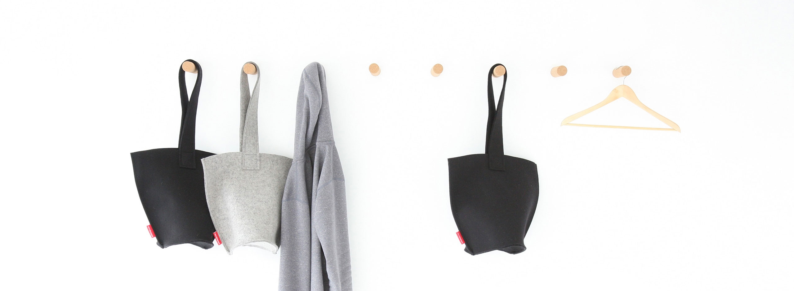 a sweater and hobo bags hang from cork peg