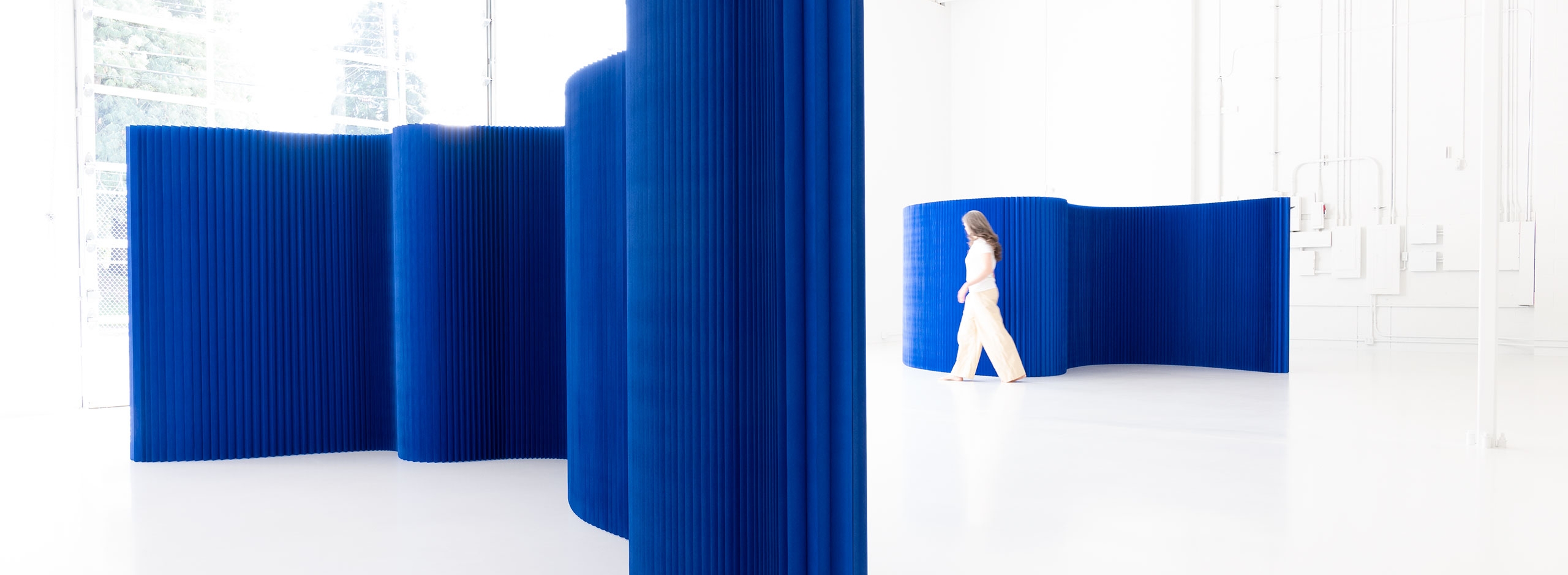 The paper wall by molo is a freestanding flexible space partition. This blue version of the softwall room divider both absorbs and radiates light.