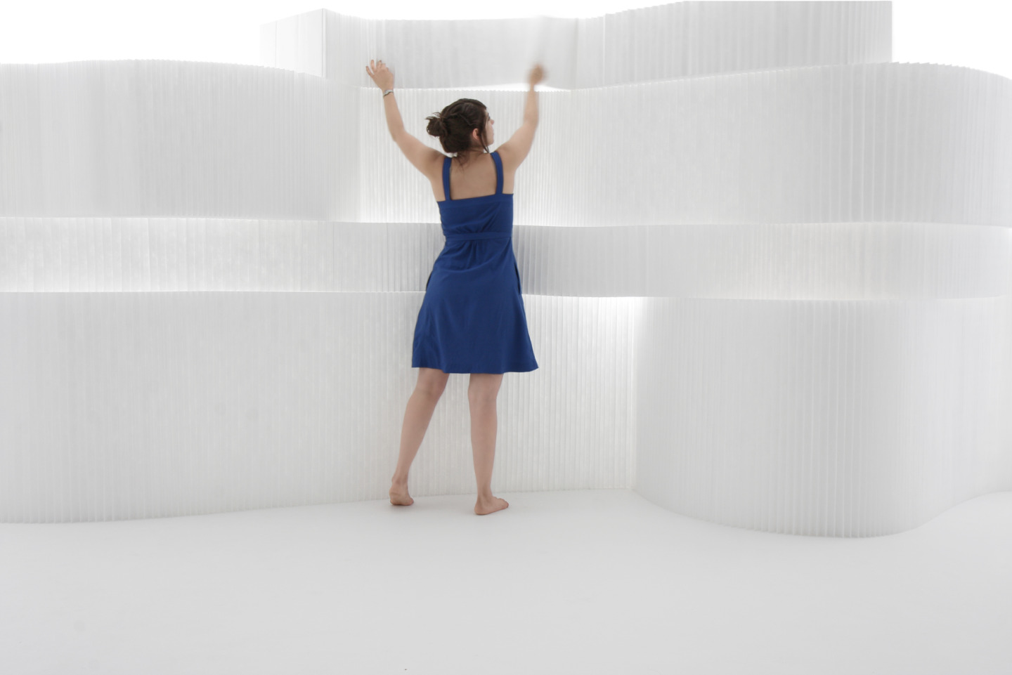woman in a blue dress arranges textile softblocks - moveable modular room divider by molo