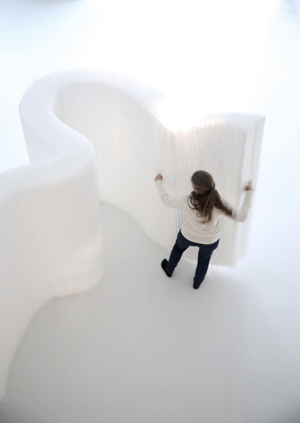 moveable room divider - woman arranges white textile softwall by molo