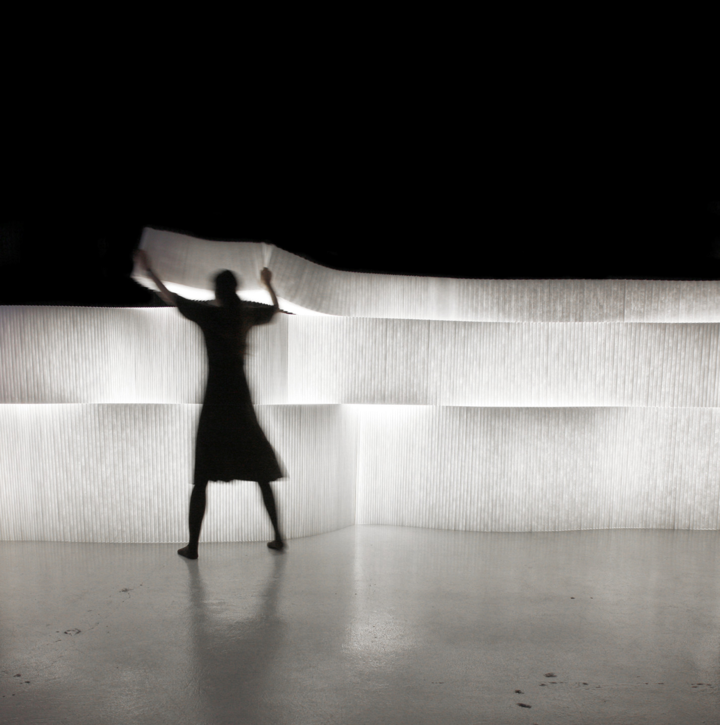 a woman arranges textile softblock with LED to form glowing space partitions - moveable modular room divider by molo