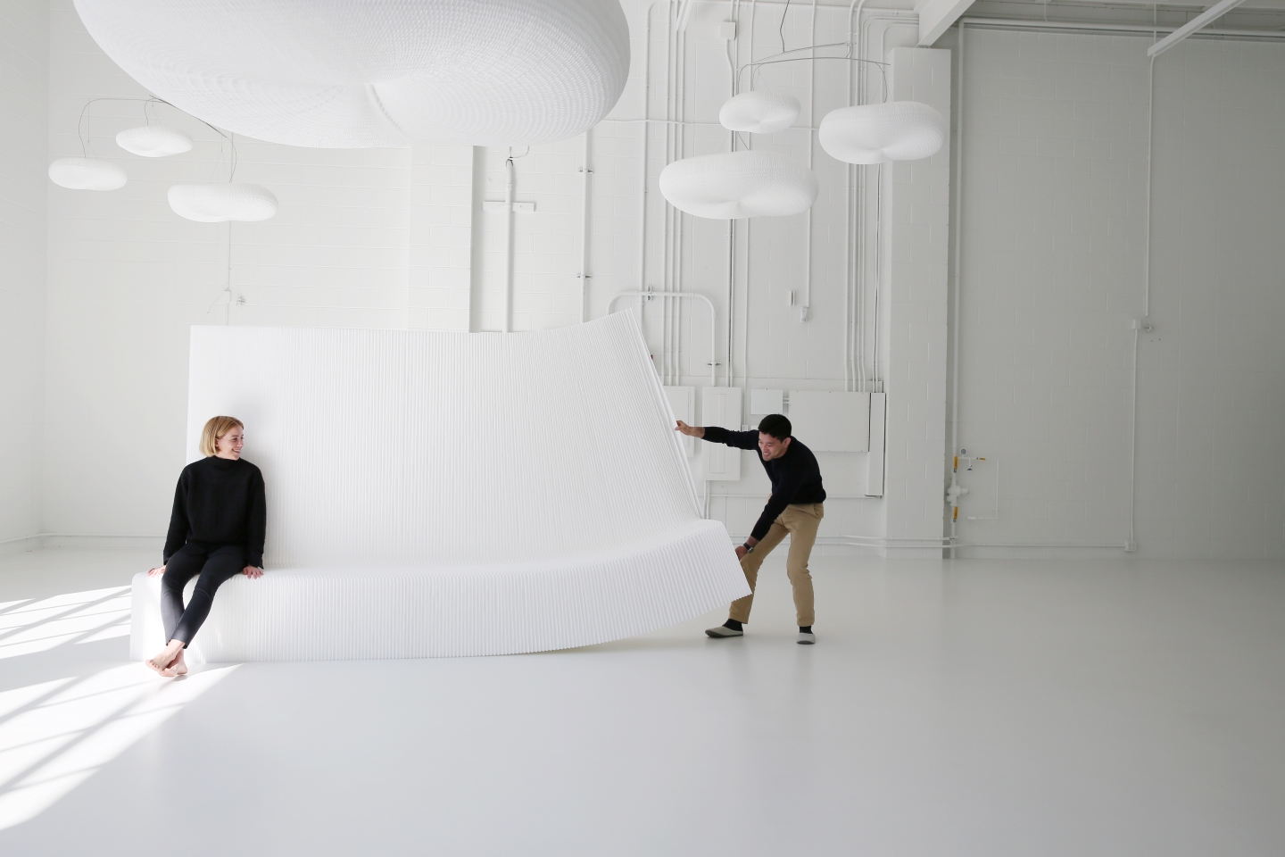 stretching open a white textile benchwall underneath a canopy of cloud mobiles