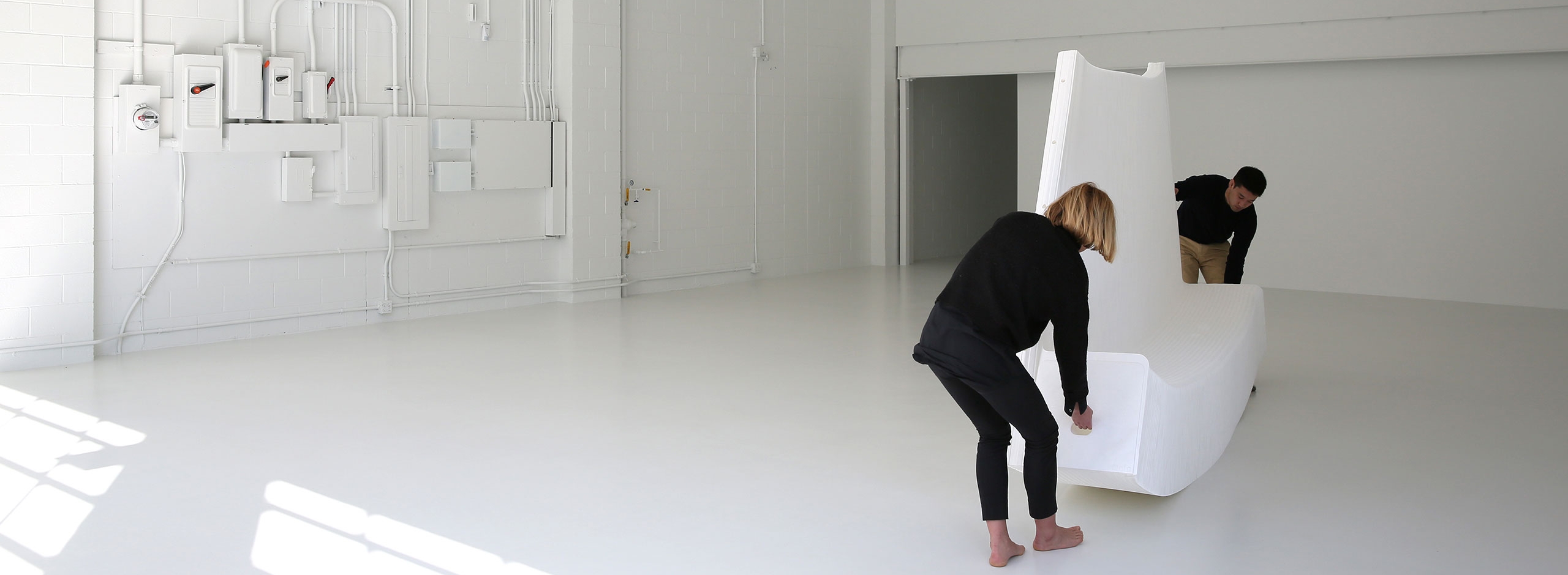 two people stretch open a white textile softwall