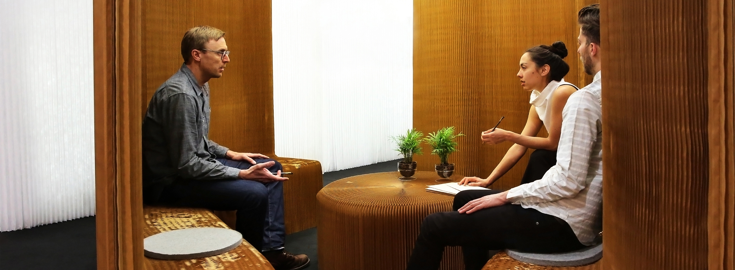 a group of people chat in a small meeting room made from connected benchwalls