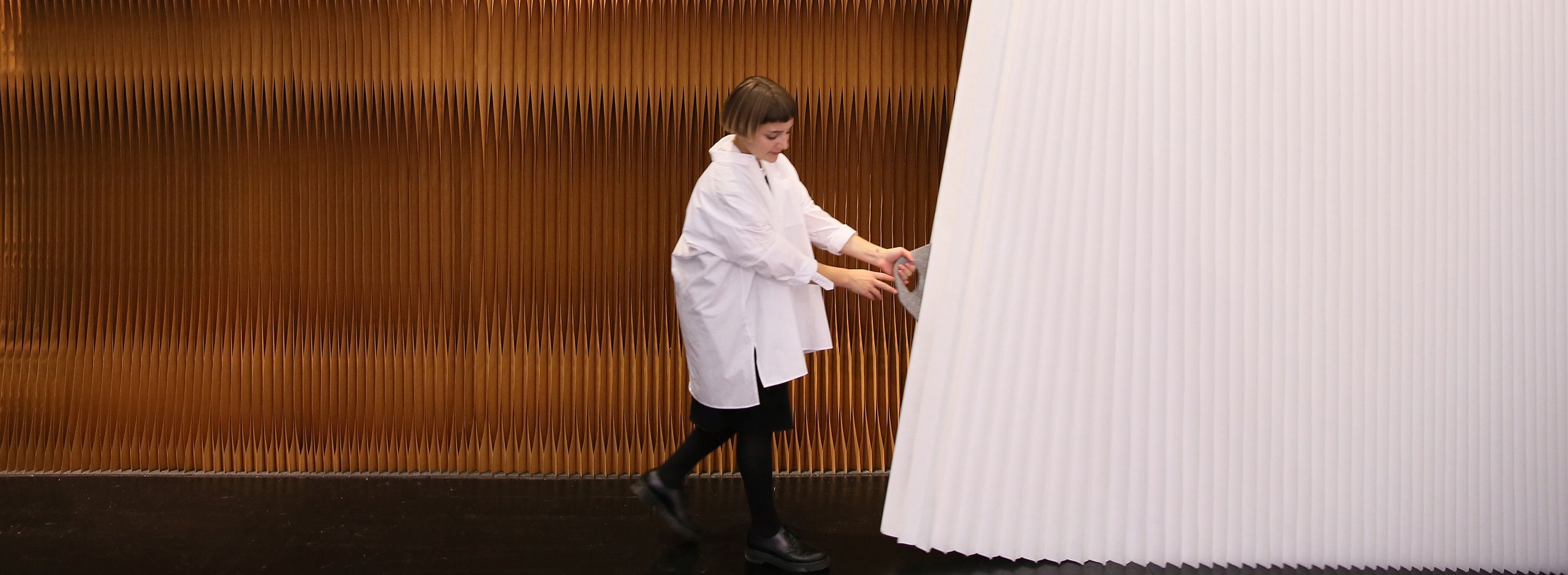 woman stretches open a white textile softwall