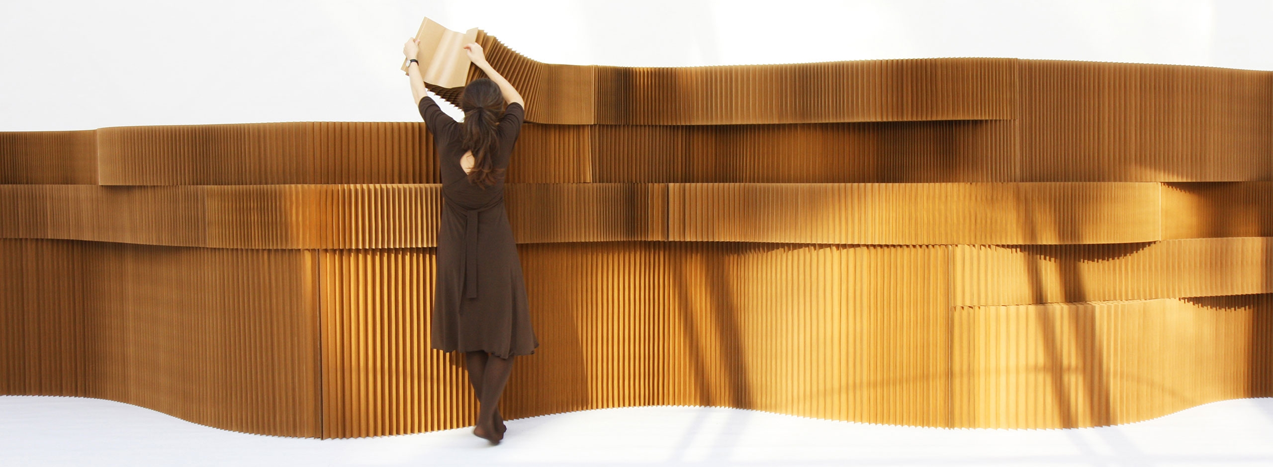 a woman arranges a series of stacked brown paper softblocks