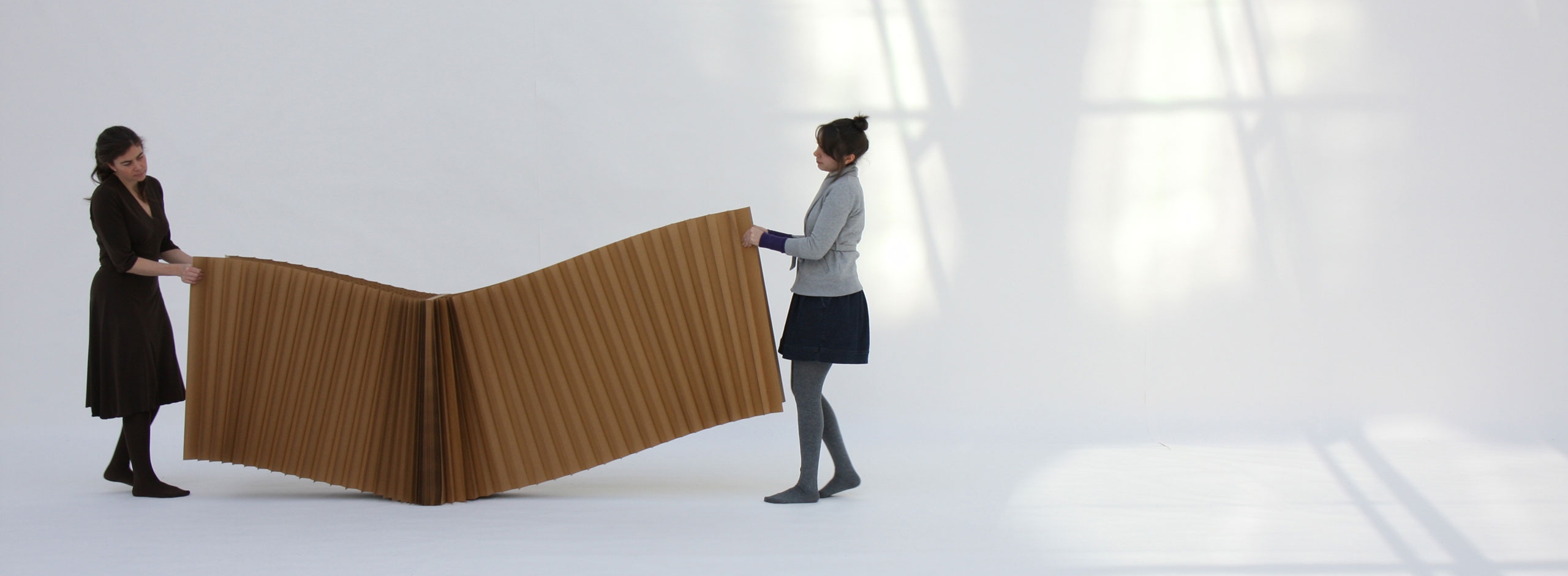 two women stretch open a brown paper softblock