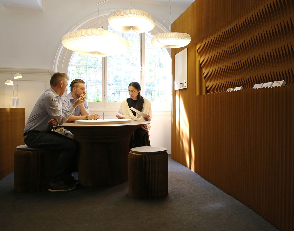 cloud lamp over folding paper furniture meeting table and softwall acoustic partition create meeting room.
