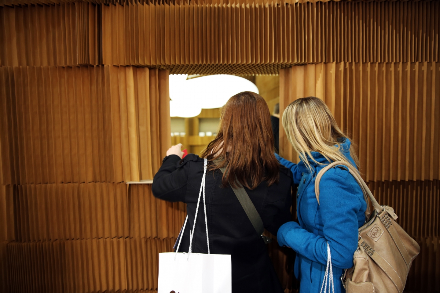 Two women peek through a window made from softblocks.