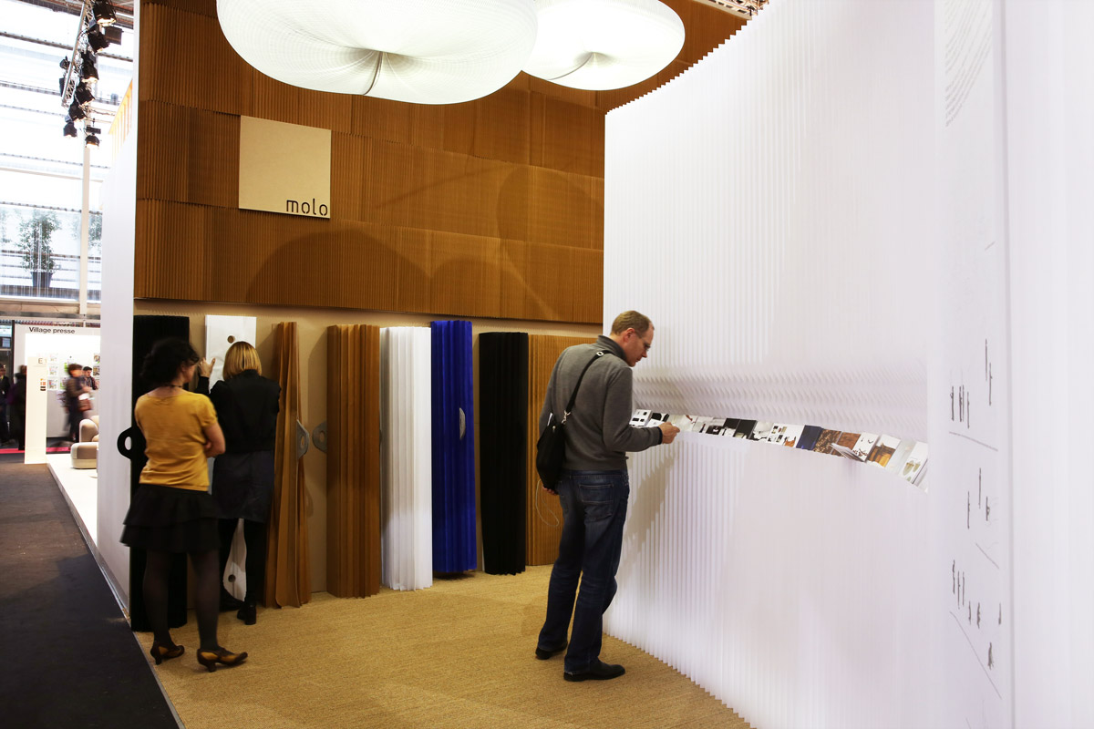 A portion of molo's installation at Maison & Objet 2014. A molo employee demonstrates softwalls to a guest while another visitor examines print materials on display.