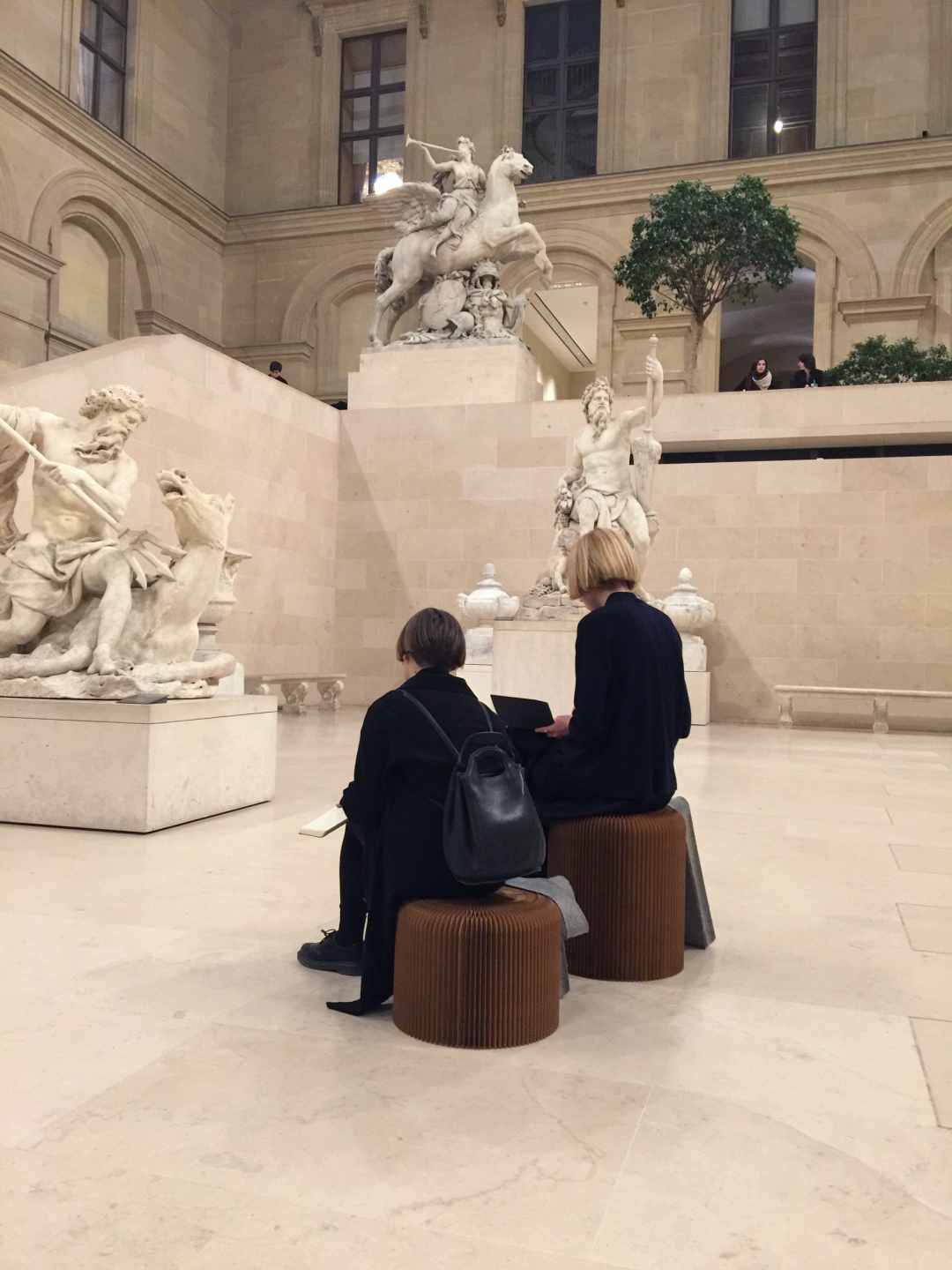 two women use softseating fanning stools as impromptu seats at the Louvre