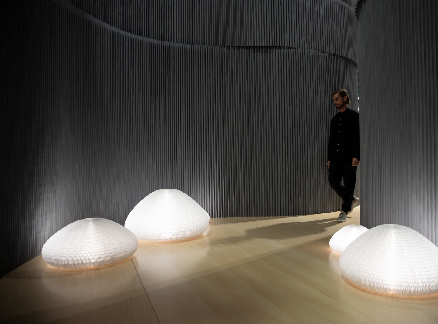 Inside a room made from softwall, a man examines molo's flexible lamps, wall partitions
