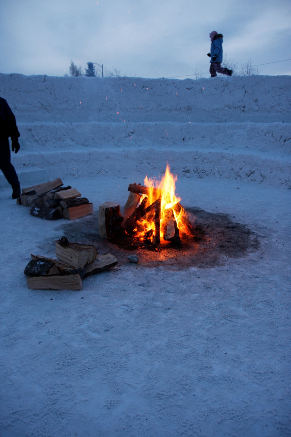 a camp fire provides a hearth at the heart of northern sky circle, an outdoor room of snow designed by Stephanie Forsythe + Todd MacAllen, in collaboration with sound artist Ethan Rose.